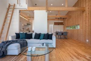 Una sala de estar con un sofá y una mesa de cristal. en Homerunner by H2 Life, en Kutchan