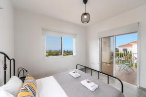 a white bedroom with a bed and a balcony at Napa Bay View Villa 3 in Ayia Napa