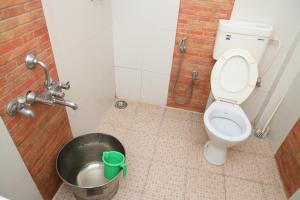 a bathroom with a toilet and a bucket at Sai Home Stay in Madikeri +16 photos