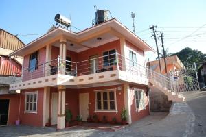 una casa roja con balcón en la parte superior. en Sai Home Stay, en Madikeri