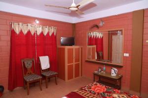 Schlafzimmer mit roten Wänden und roten Vorhängen sowie einem TV in der Unterkunft Sai Home Stay in Madikeri