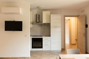 a kitchen with white cabinets and a tv on a wall at MARIS Apartments & Bedrooms in Alghero