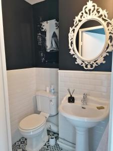 een badkamer met een wastafel, een toilet en een spiegel bij Spacieux loft en duplex in Straatsburg