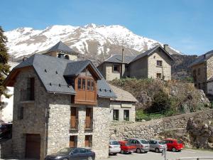 un grupo de edificios con coches estacionados frente a una montaña en Apartamentos Fidalgo en Sandiniés