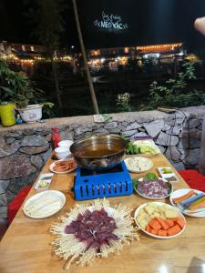 una mesa con un tazón y platos de comida. en Xúa Vừ Homestay en Mèo Vạc