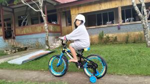a person riding a bike in front of a house at G - RIMA GARDEN HomeStay in Lengkoajang