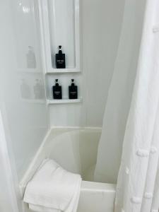 ein weißes Bad mit einer Badewanne und 2 Seifenflaschen in der Unterkunft The Lil' Yellow Door8 in Durant