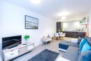 a living room with a blue couch and a tv at Spacious 2-Bedroom Apartment in the Heart of Manchester - Ideal for Families or Groups in Manchester