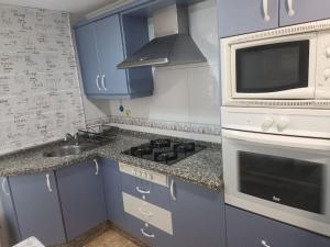 a kitchen with blue cabinets and a stove and a microwave at Piso en la Costilla-Rota in Rota