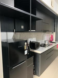 - une cuisine avec des armoires noires et un réfrigérateur noir dans l'établissement Apartment Breeze Bintaro, Tangerang Selatan, à Pondoklang