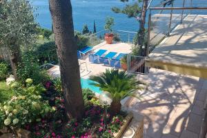un jardín con flores, una piscina y el océano en Villa VISTA LAGO, en Torri del Benaco
