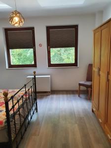 ein Schlafzimmer mit zwei Fenstern und einem Bett und einem Stuhl in der Unterkunft Haus Oveney in Bochum