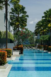 a swimming pool with palm trees in a building at Kanvaz Village Resort Seminyak in Seminyak