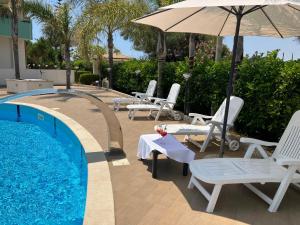 een groep stoelen en een parasol naast een zwembad bij Residence Fronte Mare in Santa Maria Del Focallo