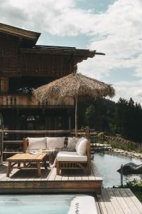 een bank op een terras naast een zwembad bij Jufenalm BOHO Hotel & Restaurant in Maria Alm am Steinernen Meer