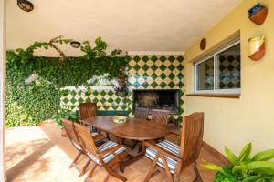 a patio with a wooden table and chairs and a fireplace at Vila Roser in L'Ametlla de Mar