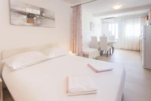 Apartments Bandić - 30 meters to the beach في تروغير: غرفة نوم بيضاء مع سرير أبيض وغرفة طعام