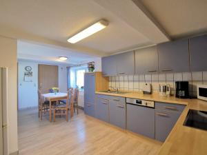 a kitchen with blue cabinets and a table with chairs at Ferienwohnung Clausen in Janneby