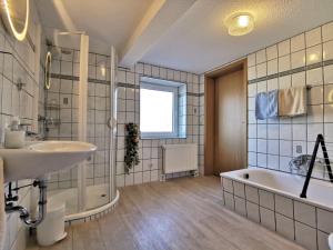 a bathroom with a tub and a sink and a bath tub at Ferienwohnung Clausen in Janneby