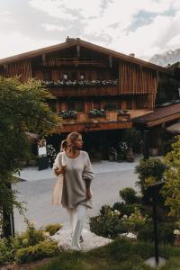Eine Frau, die vor einem Gebäude einen Pfad entlang geht. in der Unterkunft Jufenalm BOHO Hotel & Restaurant in Maria Alm am Steinernen Meer