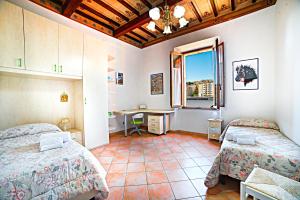 een slaapkamer met 2 bedden, een bureau en een raam bij La casa di Giulina in Siena