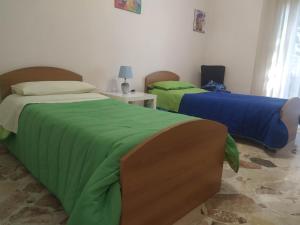サレルノにあるNel Giardino Fioritoの緑と青のカバーが付いたベッド2台が備わる客室です。
