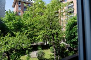 a window view of a yard with trees in front of a building at 15min metro Duomo - RHO fiera - Skyscraper Kitchen in Milan