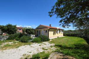 a small yellow house with a grass yard at Holiday Home Pere in Malinska