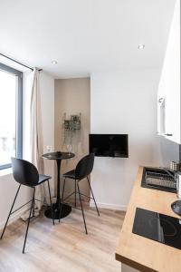 cocina con mesa y sillas en una habitación en Le doux nid - Résidence Hestia en Saint-Étienne