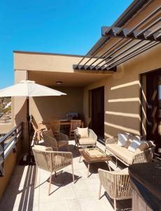 eine Terrasse mit Stühlen, einem Tisch und einem Sonnenschirm in der Unterkunft RESIDENCE SAMBRO - Jacuzzi et piscine chauffée vue mer - 4 étoiles in Les Issambres