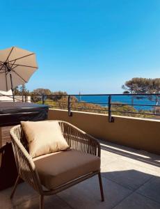 una sedia in vimini seduta su un balcone con ombrellone di RESIDENCE SAMBRO - Jacuzzi et piscine chauffée vue mer - 4 étoiles a Les Issambres