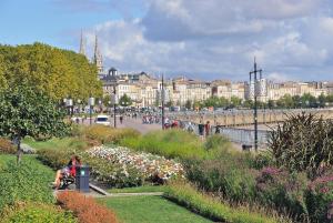 Eine Frau, die auf einer Bank in einem Park mit Blumen sitzt. in der Unterkunft *** Le studio *** 15 minutes de Bordeaux *** in Fargues-Saint-Hilaire