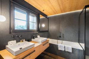 ein Badezimmer mit zwei Waschbecken und einer Badewanne in der Unterkunft Swiss Hotel Apartments - Gstaad in Gstaad