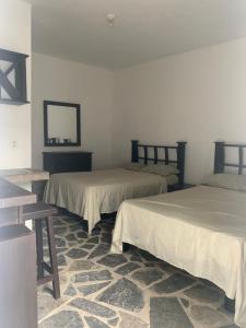 a room with two beds and a table and a mirror at Hotel/Hostal Casa Blanca in Aquismón