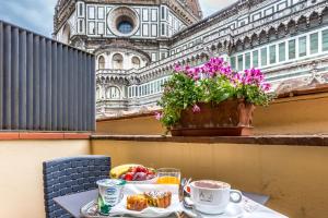 a table with food and coffee on a balcony with a building at Hotel Duomo Firenze in Florence