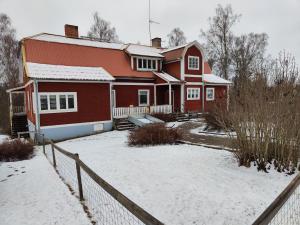 una casa roja en la nieve con una valla en Living Ludvika, en Ludvika