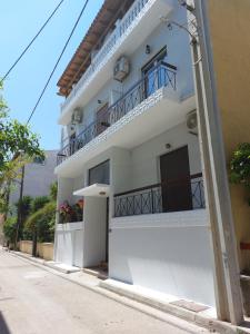 a white building with a balcony on a street at Crystal Home near Airport in Artemida