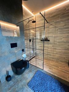 a bathroom with a shower with a black tub and a blue rug at Silesia Apartments Ustron B129 in Ustroń +31 photos