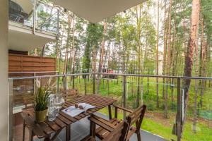 Un balcón con una mesa de madera y sillas y un bosque en Apartamenty NCNK Baltic Park w Stegnie - 500 m do plaży en Stegna