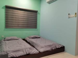 - 2 lits dans une chambre dotée d'un mur vert dans l'établissement Ipoh Klebang CP Homestay, à Ipoh