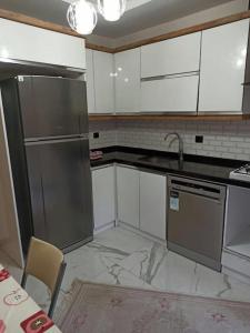 cocina con armarios blancos y nevera de acero inoxidable en Home Home en Çavuş