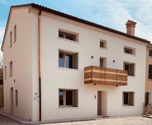 biały budynek z drewnianym balkonem w obiekcie Borgo Cortivi b&b w mieście Valdobbiadene