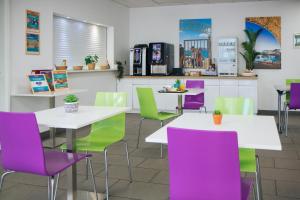 a restaurant with white tables and purple and green chairs at Twenty Business Flats Marseille Timone in Marseille