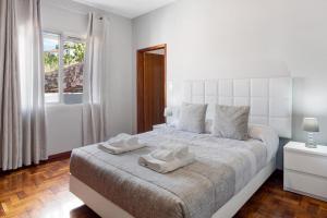 Un dormitorio con una cama blanca con dos toallas encima. en Estrela House, en Venda do Atalhinho