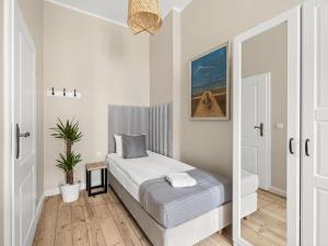 małą sypialnię z łóżkiem i lustrem w obiekcie Boho Rooms Sopot w mieście Sopot