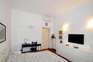 um quarto com uma cama e uma secretária com uma televisão de ecrã plano em Trilocale Centrale - Buenos Vibes em Milão