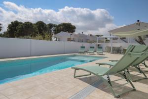 ein Pool mit Stühlen und einem Sonnenschirm neben einem Pool in der Unterkunft VILLA BELLA in L'Ampolla