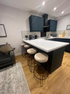 a kitchen with a white counter and bar stools at Gorgeous Newly Renovated 2 Double Bed Flat in Swansea