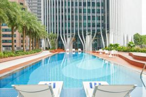 a swimming pool with two chairs and a building at Citadines Raffles Place Singapore in Singapore