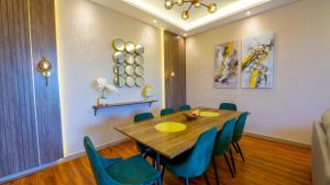 GOODWOOD SUITES HOMES VACATION في دبي: غرفة طعام مع طاولة خشبية وكراسي زرقاء